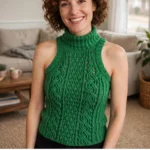 Woman wearing a kelly green cable turtleneck crochet top in a living room