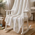 White Tunisian crochet baby blanket draped over a rocking chair