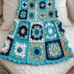 Ocean blue granny square baby dress laid flat