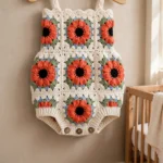 Coral poppy granny square baby romper on a hanger
